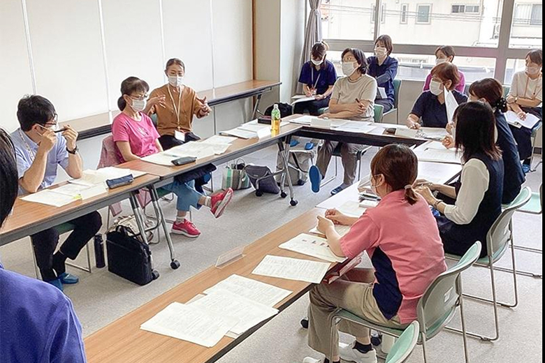 机を囲んで研修に参加するスタッフたち