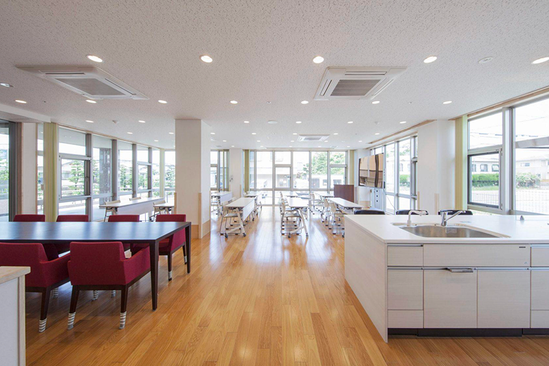 大きな窓から光が差し込む、キッチン付きの広いリビング・共用スペース
