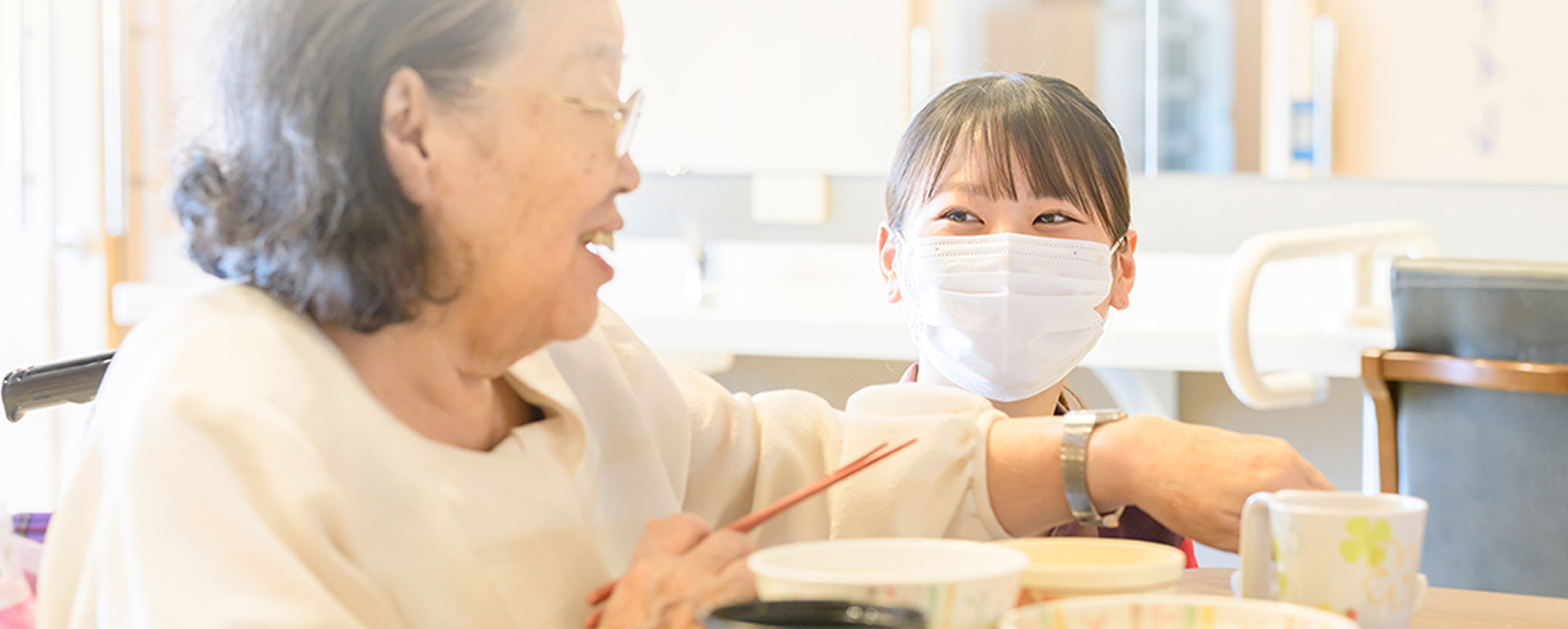 食事中の利用者と笑顔で話すスタッフ