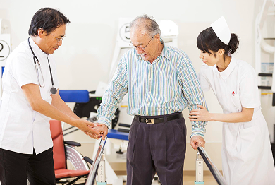 医師と看護師に支えられて歩く利用者